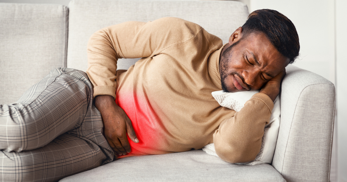 Man lying on couch, holding stomach in pain