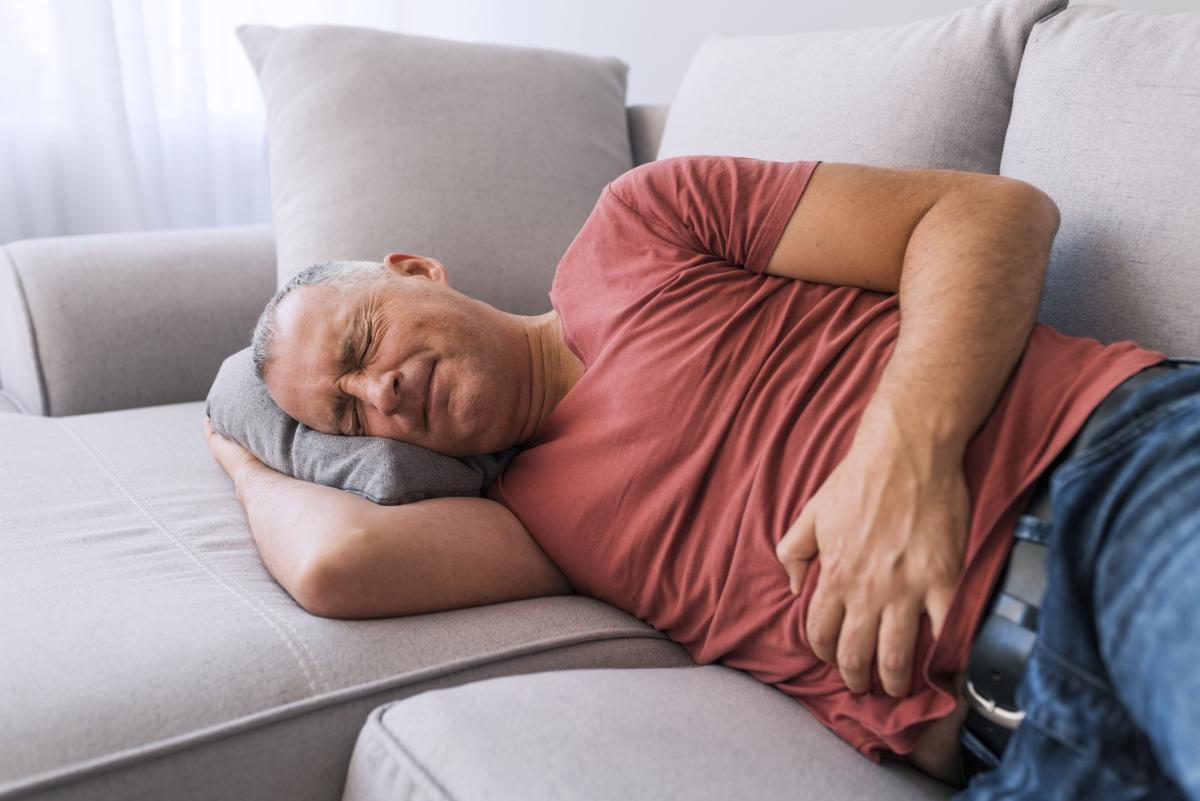 Man laying on couch holding stomach