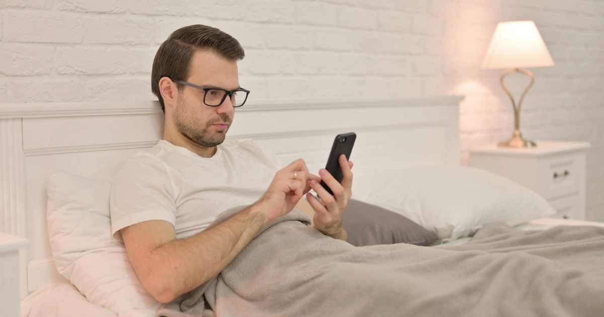 Man sitting in bed on phone