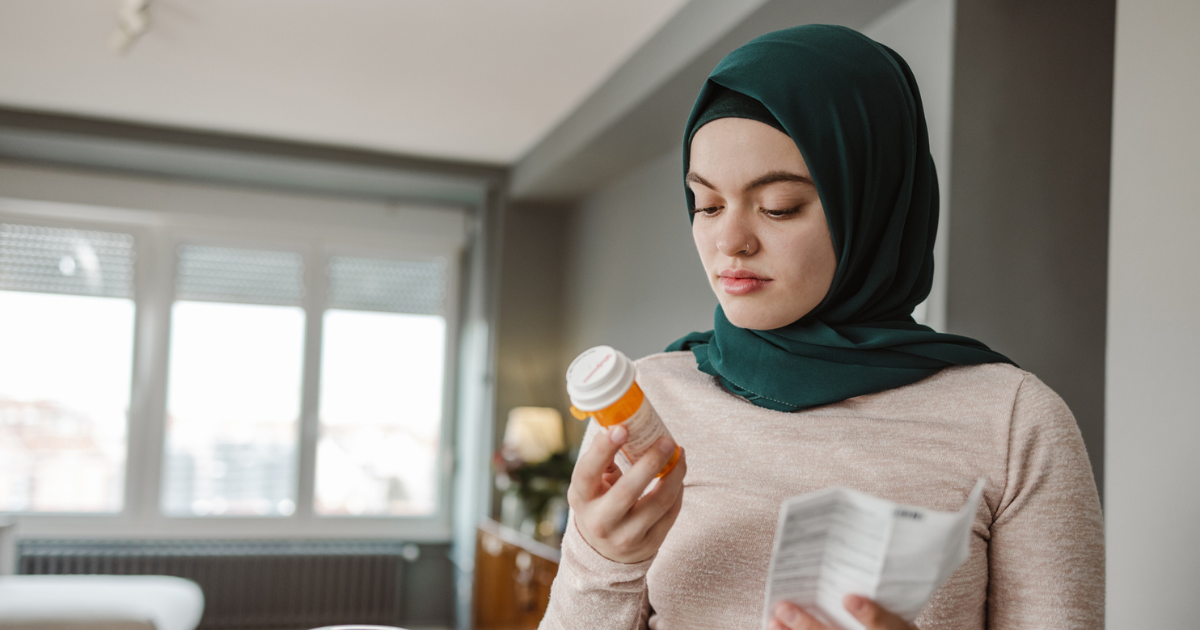 Woman wearing a hijab holding a pill bottle