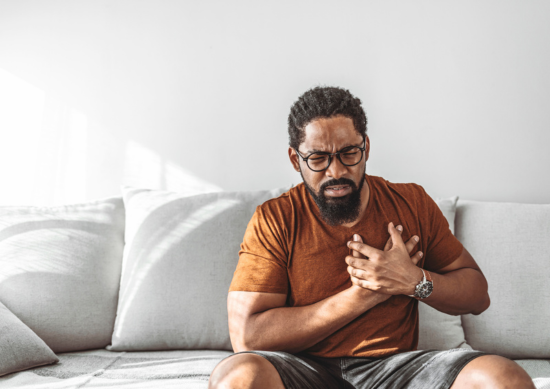 Man sitting on the couch holding his chest