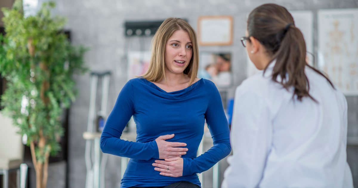 Woman holding her stomach talking to a doctor