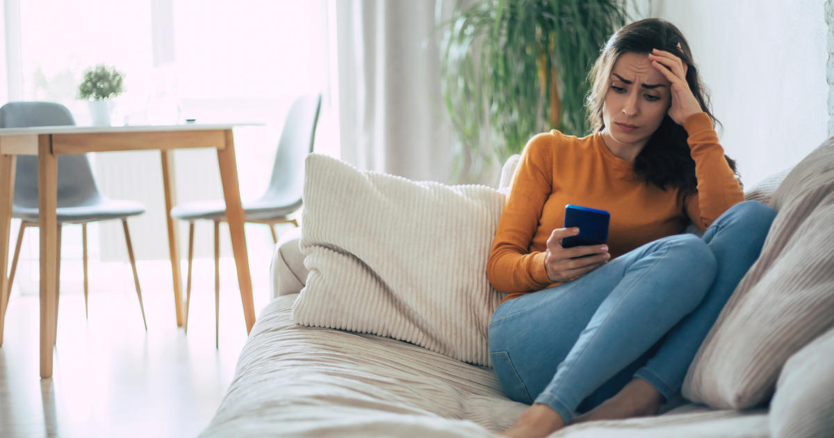 Woman sitting on couch looking at her phone