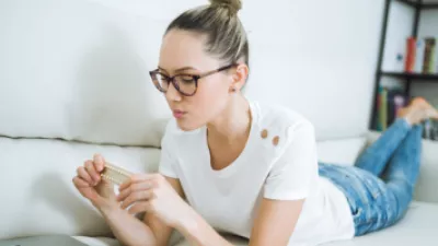 Woman laying on the couch holding a pack of birth control pills