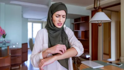 Woman wearing a hijab scratching her forearm