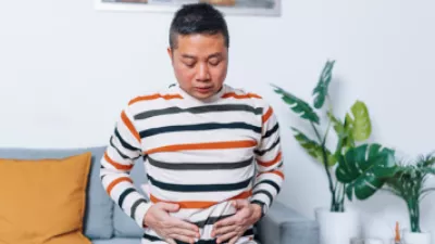 Man sitting on the couch holding his stomach