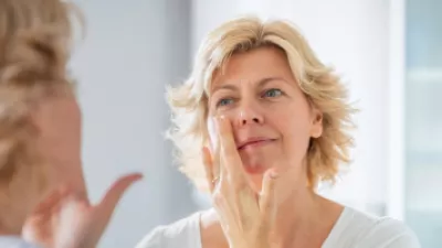 Woman applying cream to her face