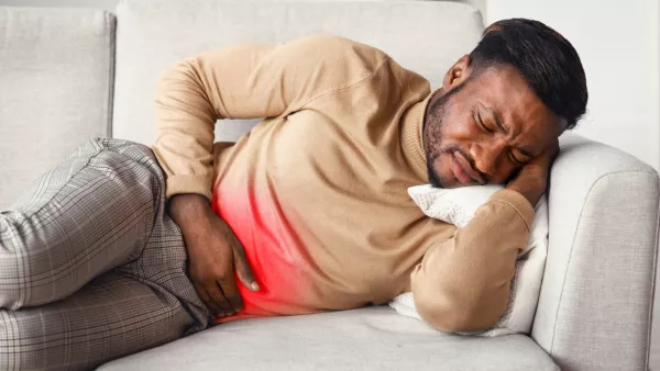 Man lying on couch, holding stomach in pain