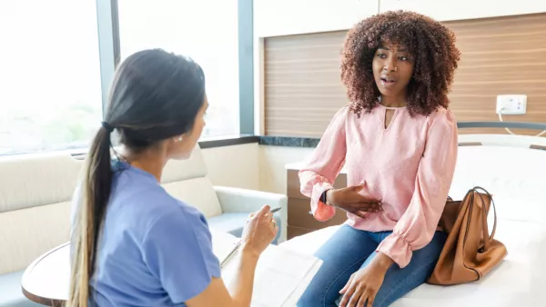 Woman holding her stomach in pain, talking to nurse