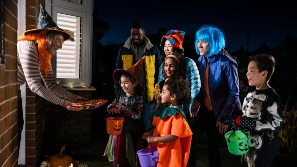 Woman handing candy to group of trick-or-treaters