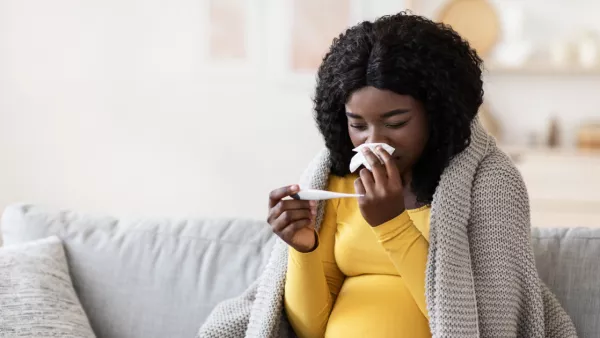 Pregnant woman holding tissue and thermometer