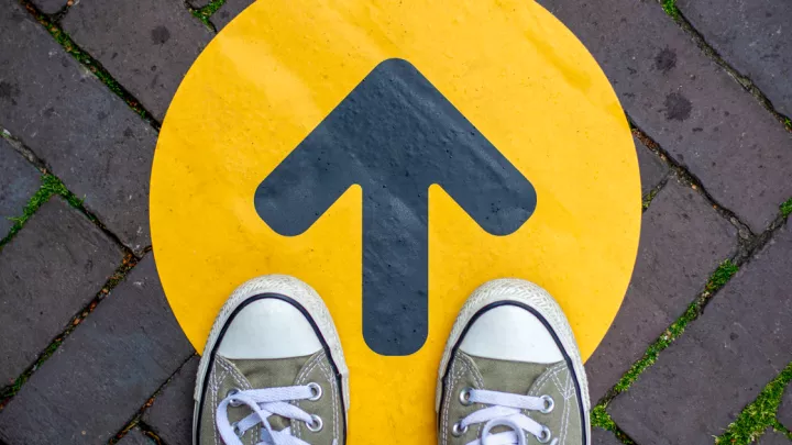 Feet standing on top of a yellow arrow