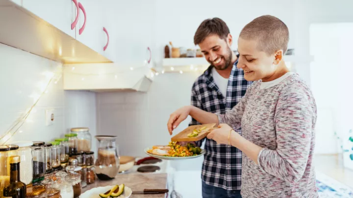Woman with cancer cooking dinner with her husband