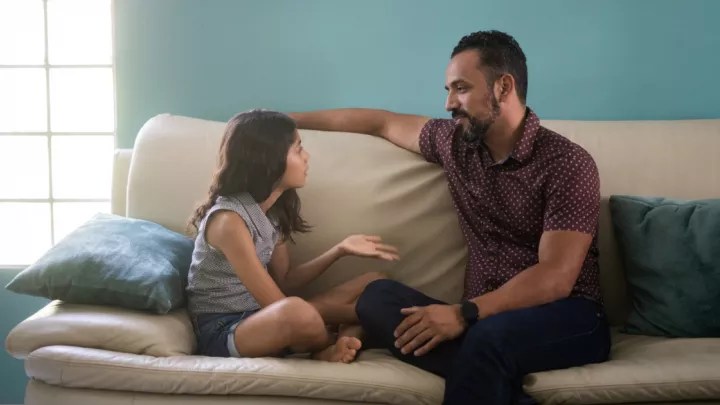 Man sitting, talking to his daughter on the couch