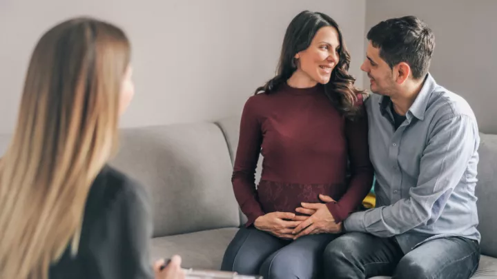Husband and pregnant wife talking to genetic counselor