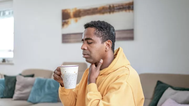 Man holding his throat drinking tea