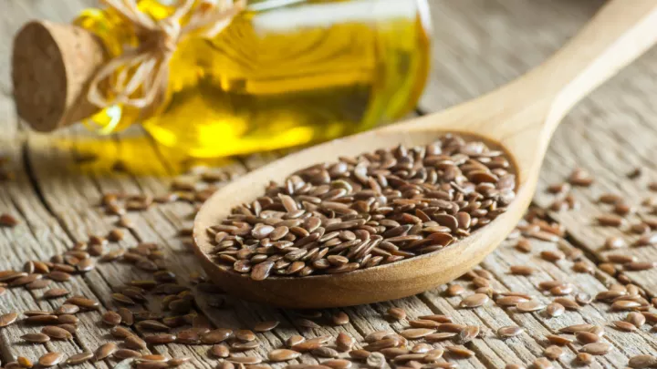 Spoonful of seeds next to a bottle of oil