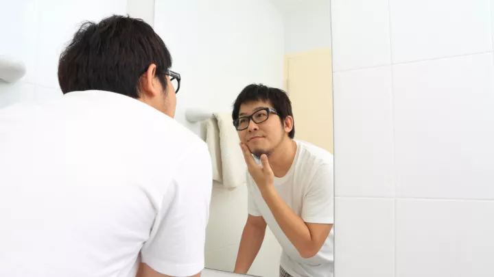 Man looking at facial hair in mirror