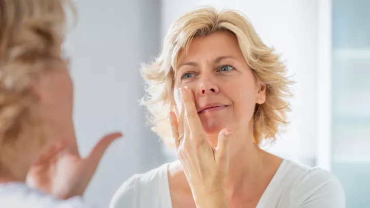 Woman applying cream to her face