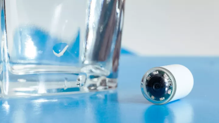 Video capsule sitting next to a glass of water