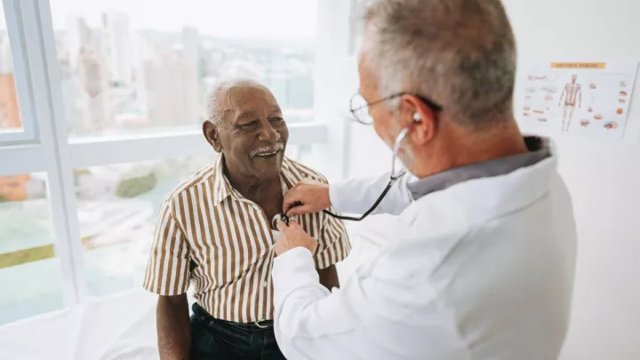 Doctor listening to man's heart