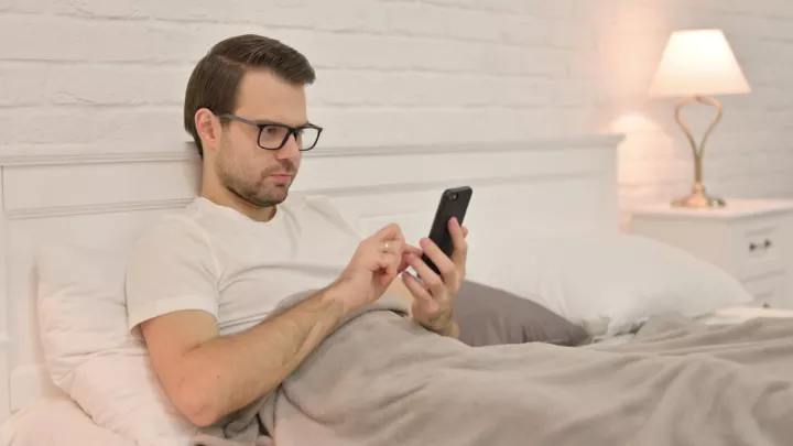 Man sitting in bed on phone