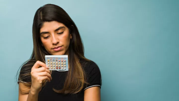 Woman holding birth control pills