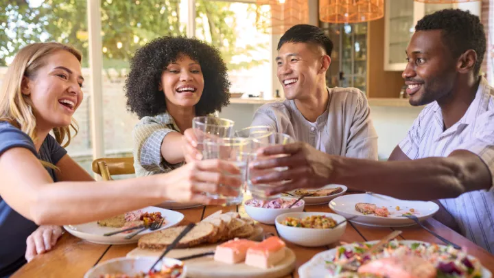 Two men and two women toasting with glasses of water