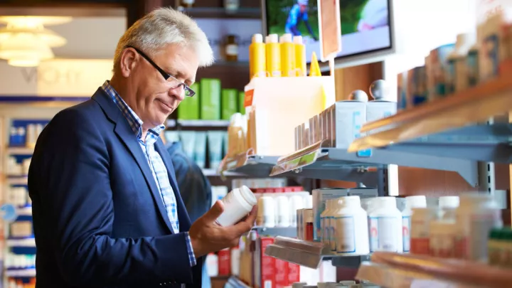 Man looking at pill bottle in store aisle