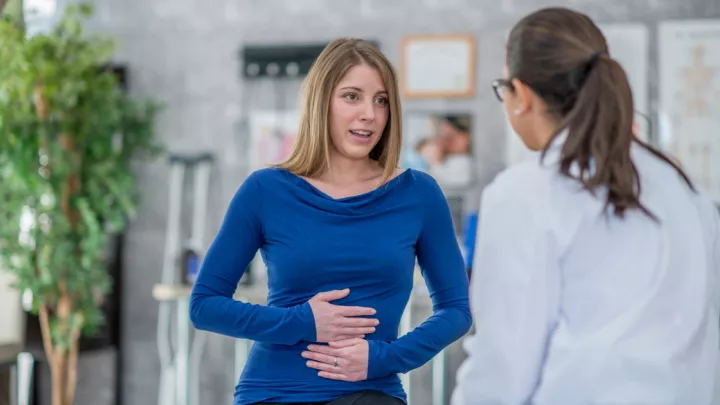 Woman holding her stomach talking to a doctor